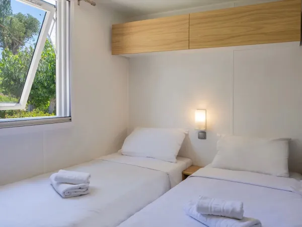 Ein Schlafzimmer mit Einzelbetten im Roan-Mobilheim Supreme mit 2 Bädern.