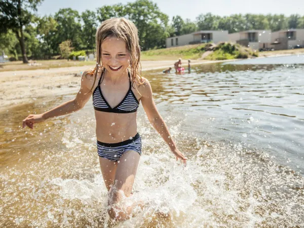 Mädchen spaziert durch einen natürlichen Pool auf dem Roan-Campingplatz De Schatberg.