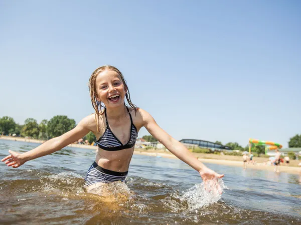 Mädchen schwimmt im Naturpool auf dem Roan Luxury Camping De Schatberg.