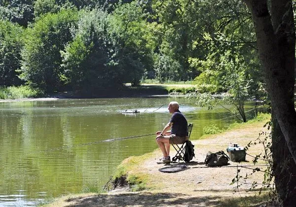 Mann beim Angeln im Fischteich des Campingplatzes Domaine de la Brèche in Roan.