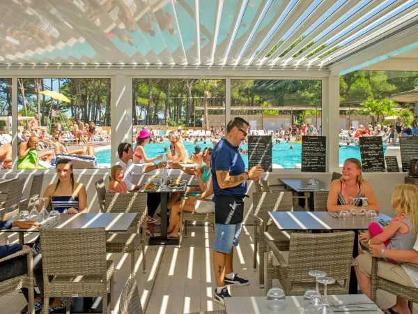 Eine volle Terrasse am Pool auf dem Campingplatz Roan Le Castellas.