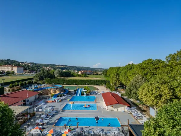 Das Schwimmbad mit Rutschen und angrenzender Terrasse auf dem Campingplatz Roan Château de Galaure.