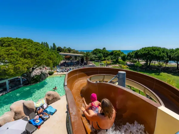 Mutter und Kind rutschen die Rutsche auf dem Campingplatz Arinella Bianca in Roan hinunter.