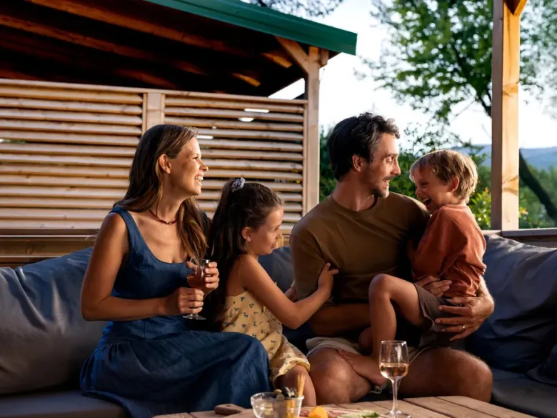 Vater und Kinder amüsieren sich auf dem Sofa des Mobilheims auf dem Roan-Campingplatz Le Petit Mousse.