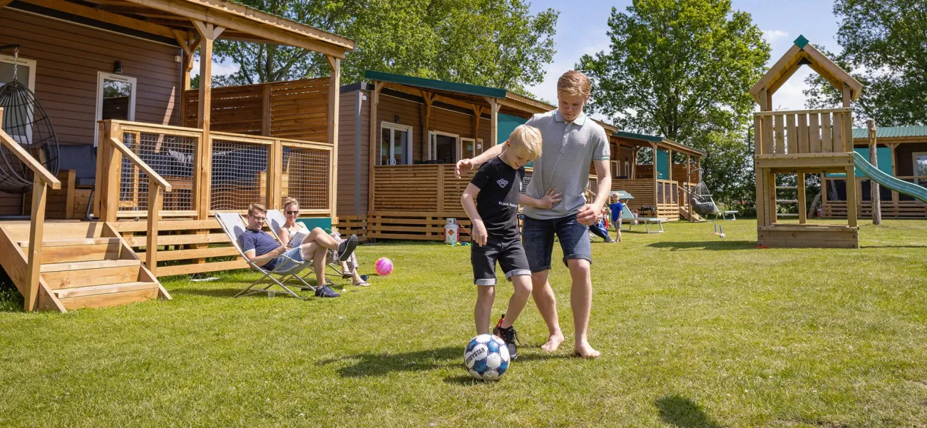 Kinder spielen Fußball vor einem Wohnmobil auf einem Roan-Campingplatz.